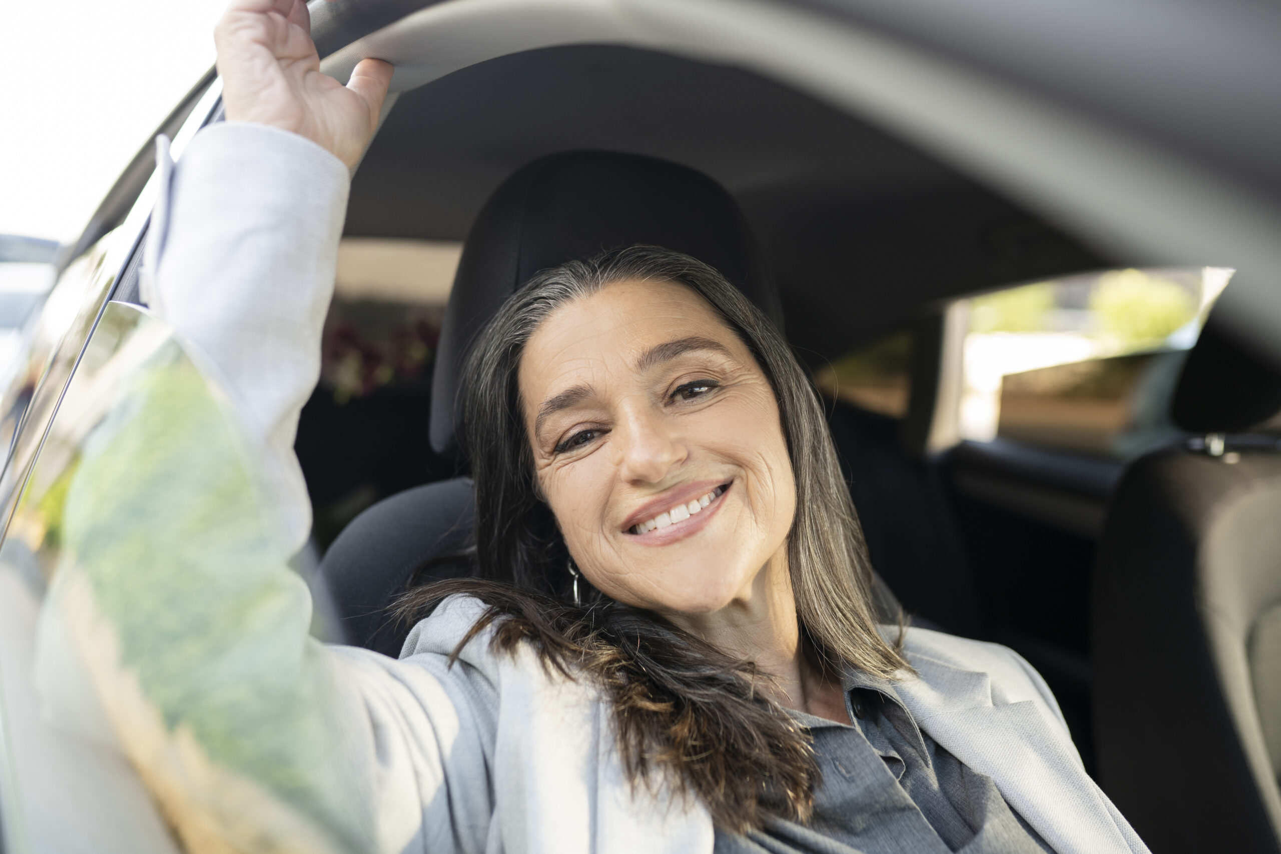 a senior businesswoman in a taxi in the back seat, and leaning on the windows looks out at the city. Beautiful smiling woman sitting in the truck. The lady is looking out the window and dreaming
